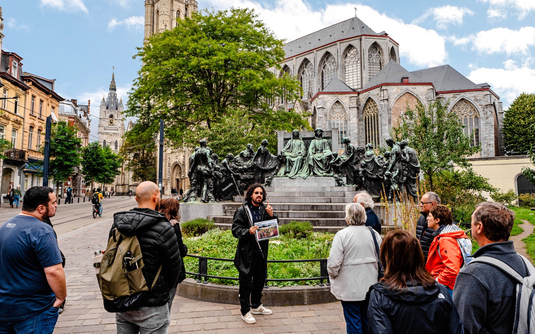 Tour group listening to a guide near a historic monument in Ghent city center, Belgium.
