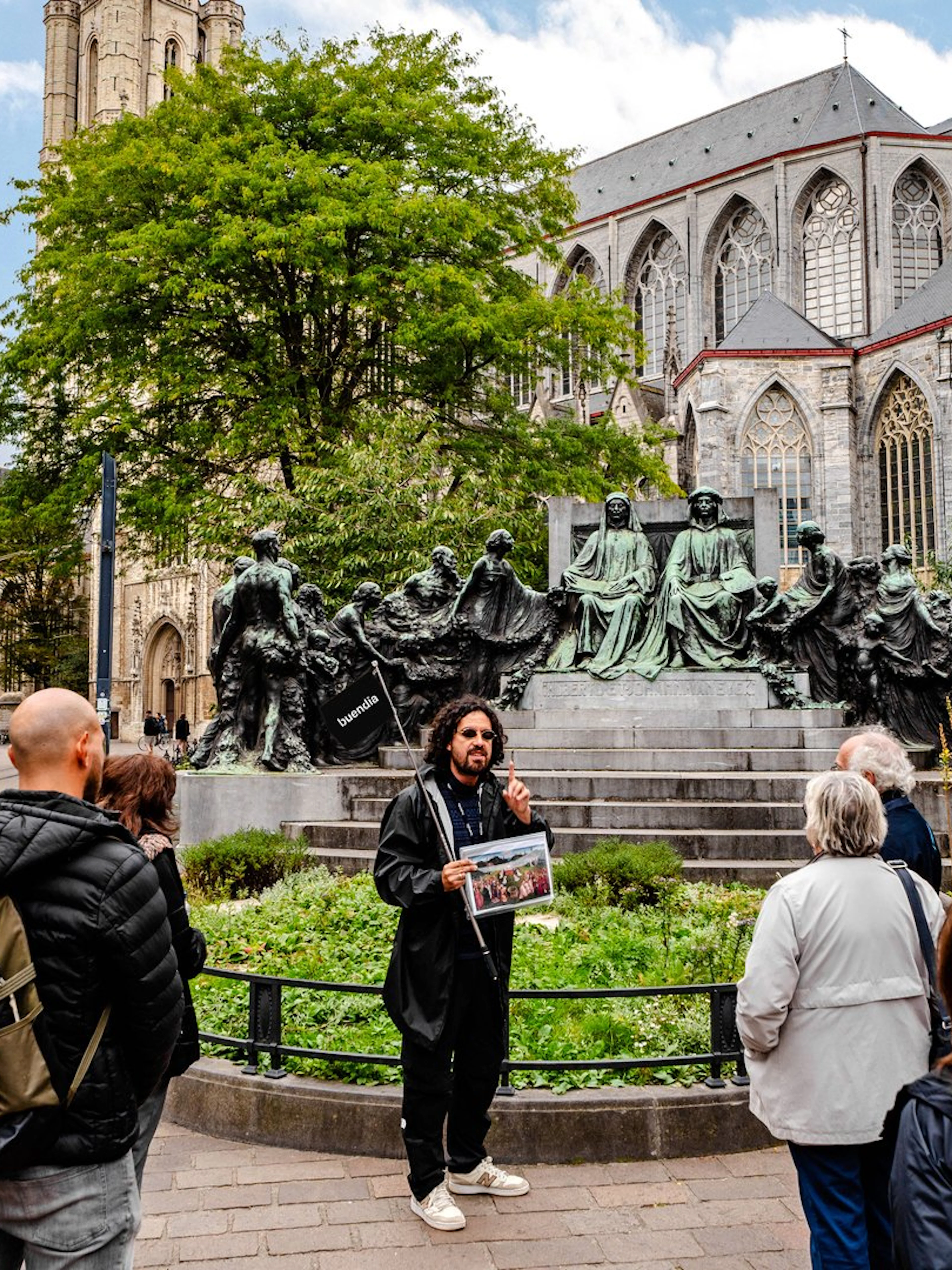 Tour group listening to a guide near a historic monument in Ghent city center, Belgium.