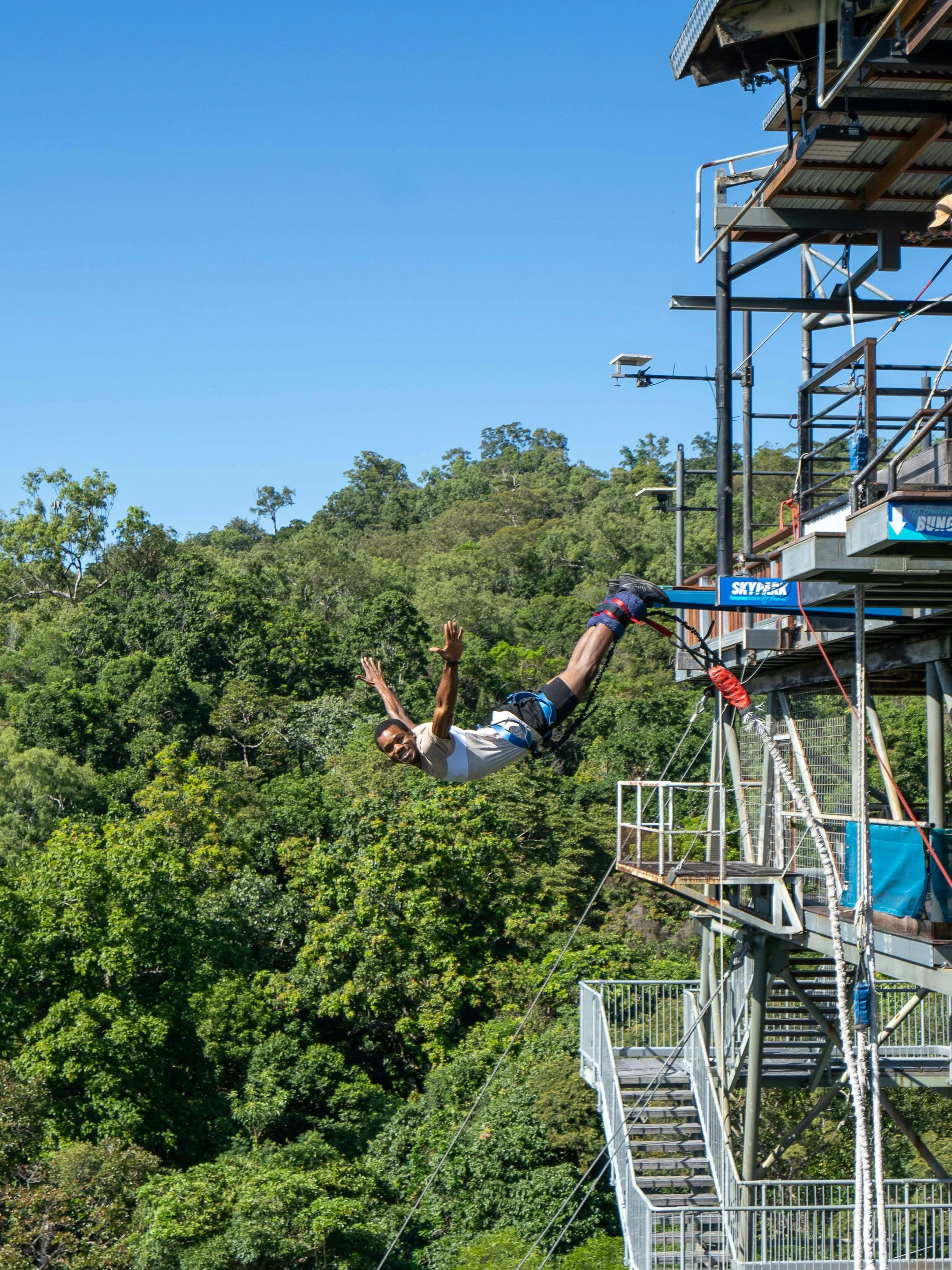 Bungy jump swan dive from platform at Skypark Cairns, surrounded by lush forest.