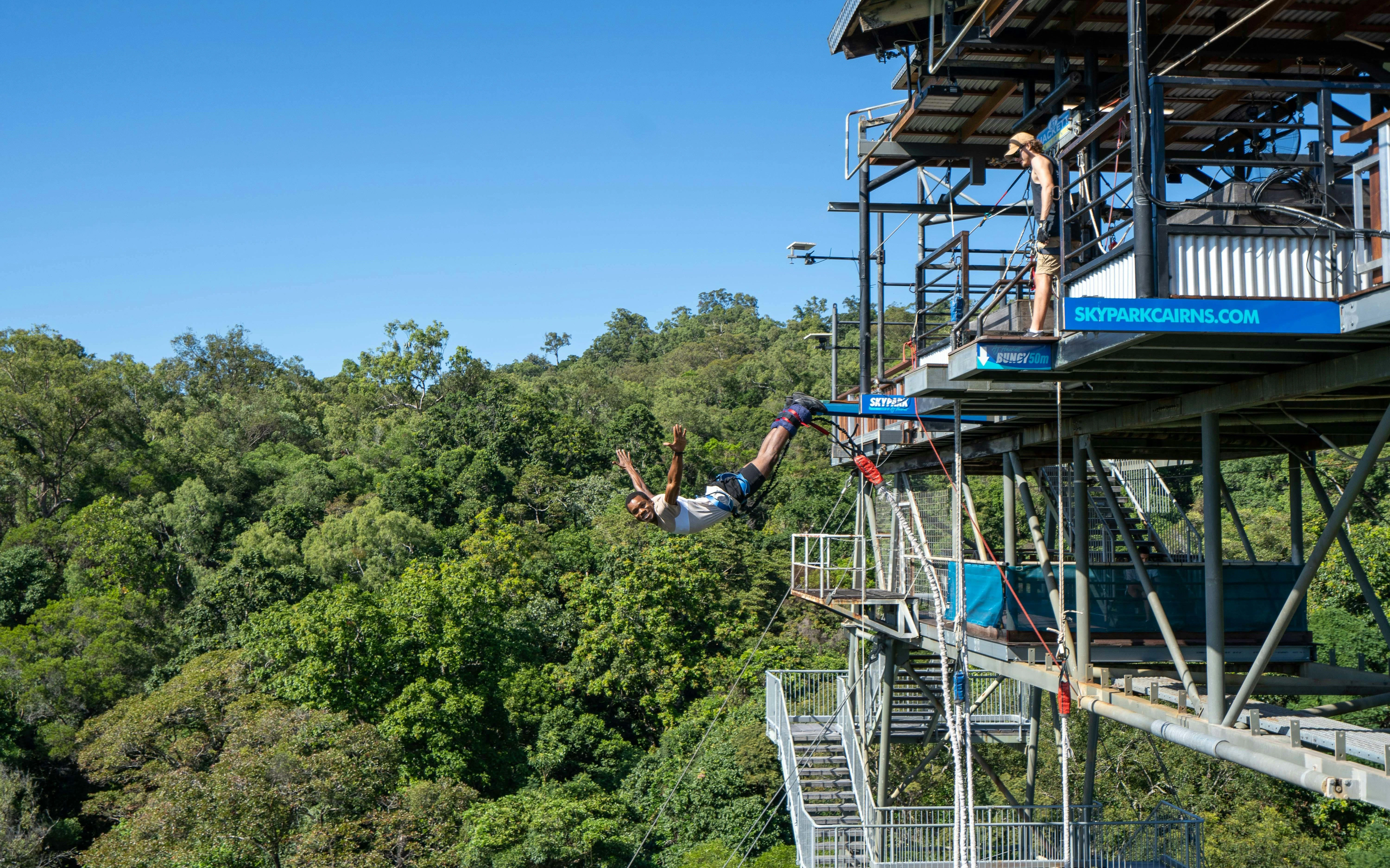 Bungy jump swan dive from platform at Skypark Cairns, surrounded by lush forest.