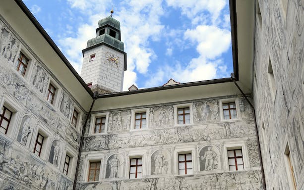Ambras Castle Innsbruck courtyard with detailed frescoes and clock tower.