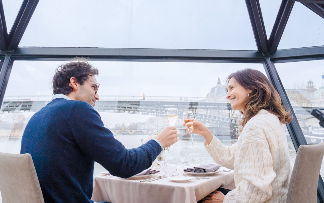 Couple enjoying lunch with champagne on a Seine River sightseeing cruise in Paris.