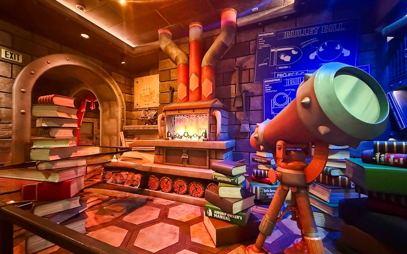 Universal Studios Hollywood attraction with telescope and stacked books in themed room.