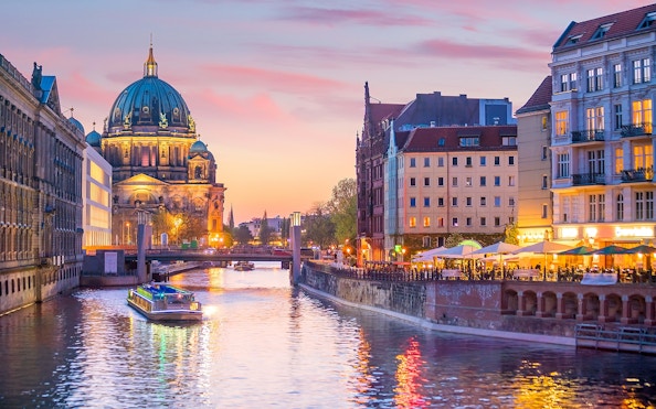 Cruise boat on the river with Berlin Cathedral in the background at sunset.