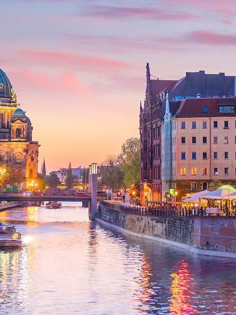 Cruise boat on the river with Berlin Cathedral in the background at sunset.