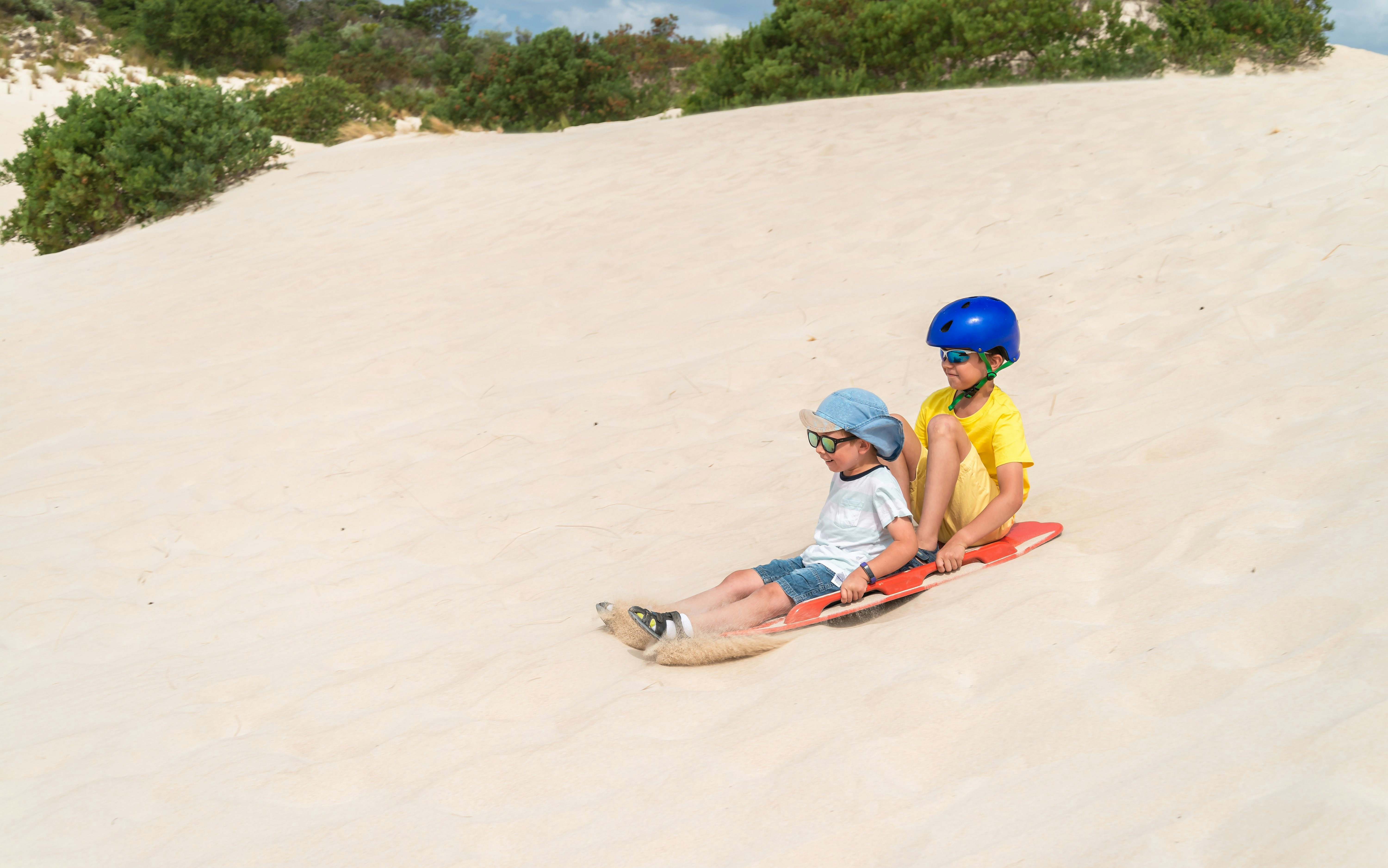 Children sandboarding down a dune, Kangaroo Island, South Australia.