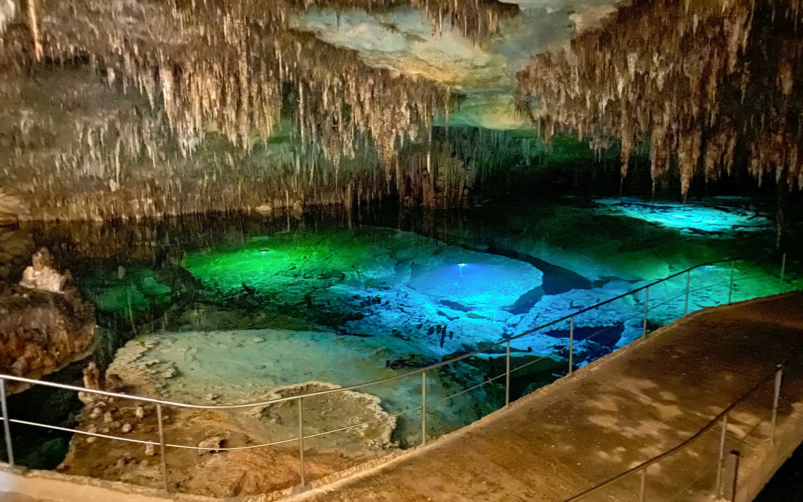 Stalactites above illuminated waters in Lake Martel cave, Mallorca.