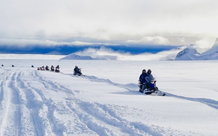 Guests snowmobiling from Gullfoss waterfall across snowy Icelandic landscape.