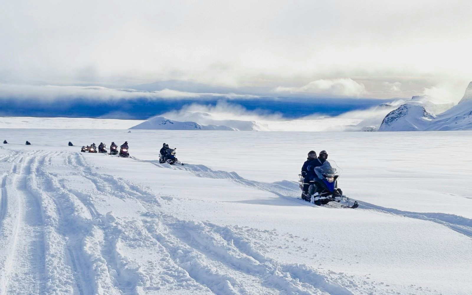 Guests snowmobiling from Gullfoss waterfall across snowy Icelandic landscape.