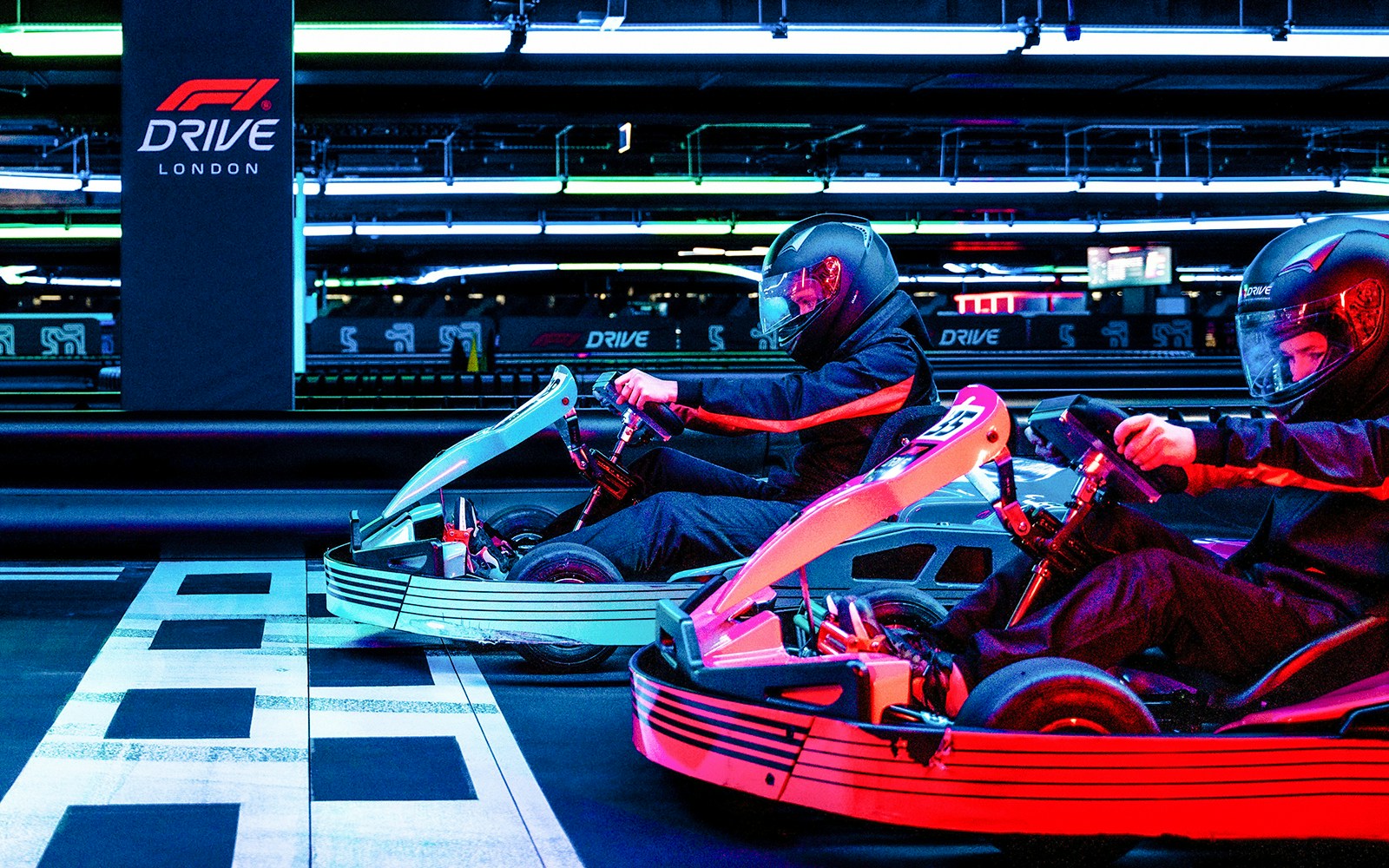 Guests racing go-karts at F1 London Mixed session indoor track.