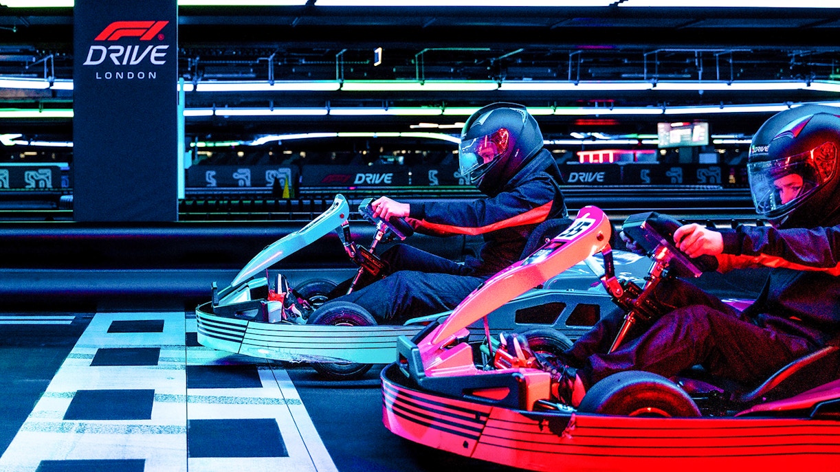 Guests racing go-karts at F1 London Mixed session indoor track.
