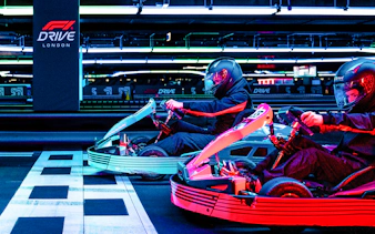 Guests racing go-karts at F1 London Mixed session indoor track.