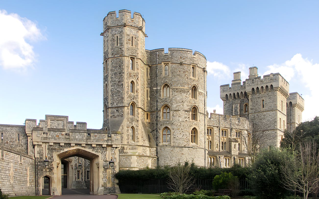Windsor Castle stone towers and entrance gate under blue sky.