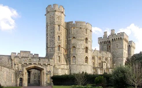 Windsor Castle stone towers and entrance gate under blue sky.
