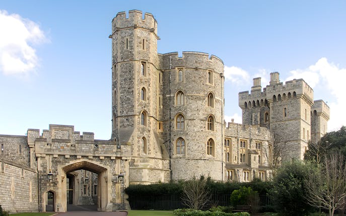 Windsor Castle stone towers and entrance gate under blue sky.