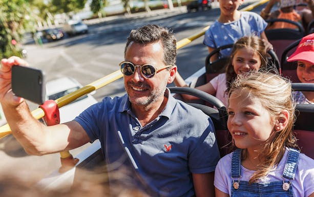 Father and daughter enjoying a Bangkok city sightseeing tour on an open-top bus.