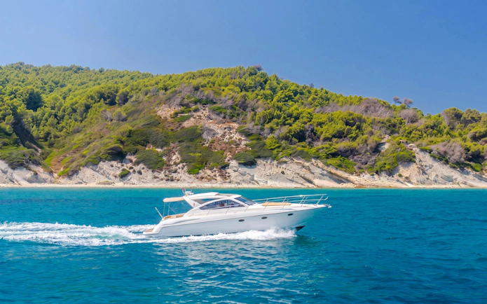 Speedboat cruising near Sazan Islands, Albania with lush green hills in the background.