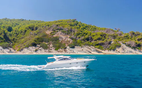 Speedboat cruising near Sazan Islands, Albania with lush green hills in the background.