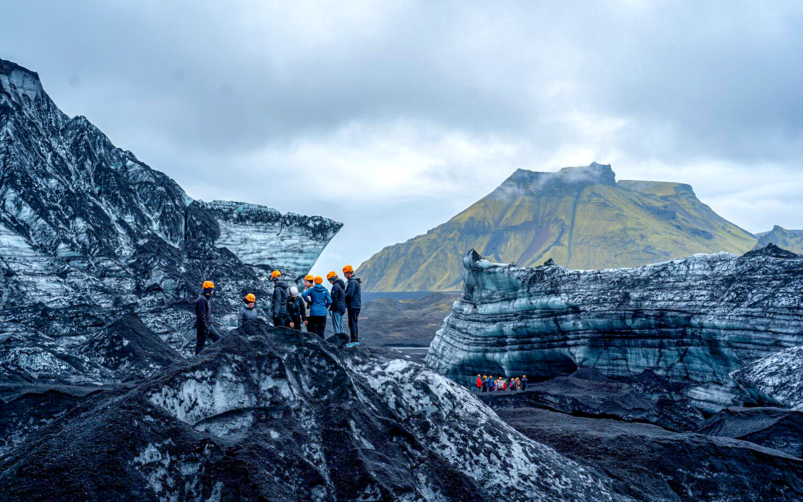 Tour guide assisting group on Katla Ice Cave hike in Iceland.