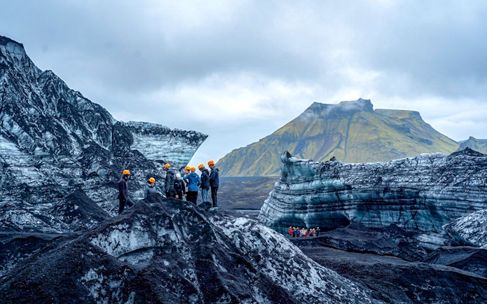Tour guide assisting group on Katla Ice Cave hike in Iceland.