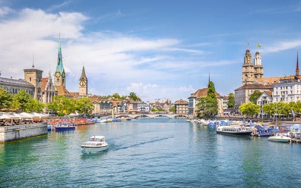 Zürich city center with Limmat River, historic buildings, and boats, Switzerland.