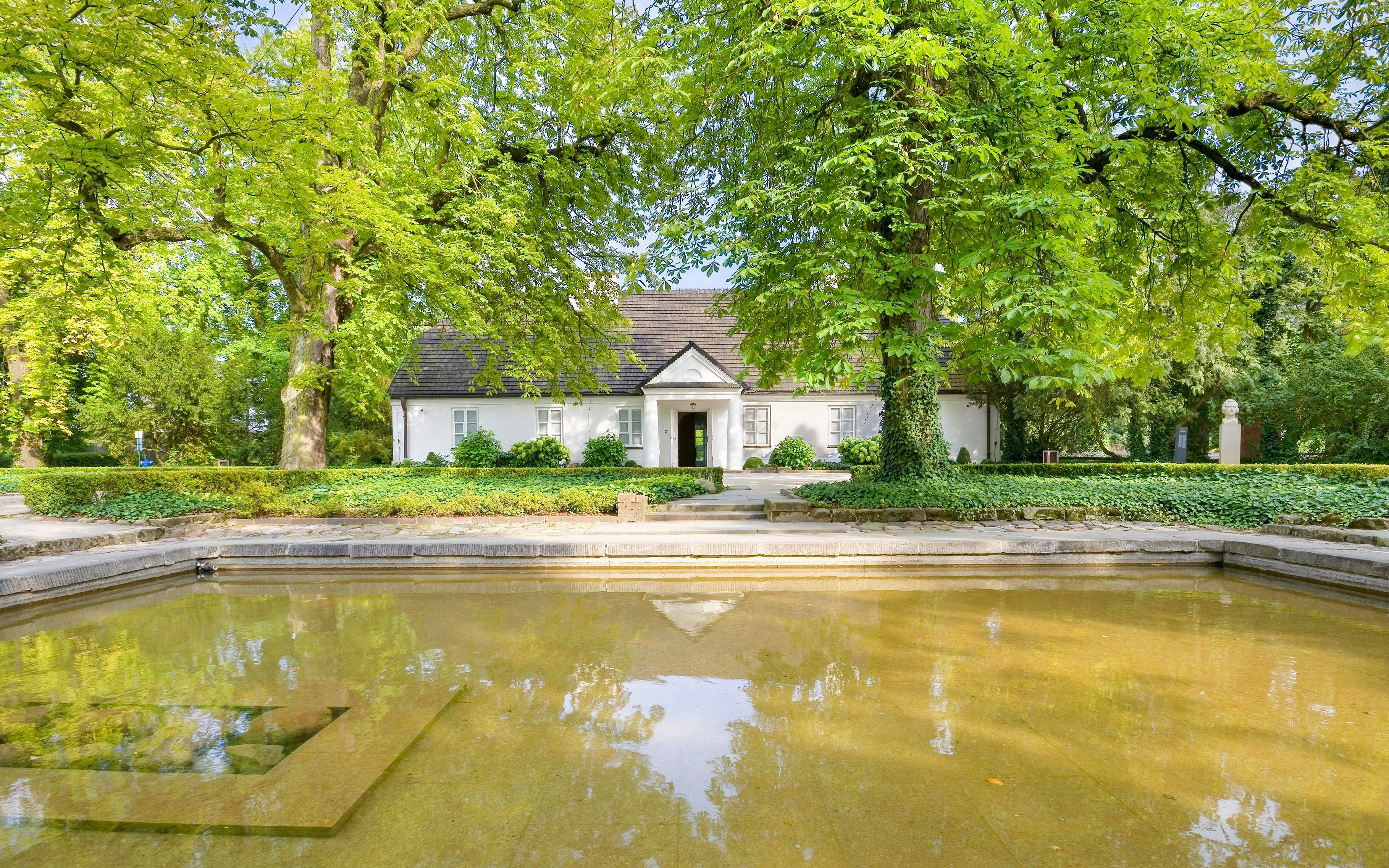 Birthplace of Frederick Chopin in Żelazowa Wola, surrounded by lush greenery and a reflecting pond.