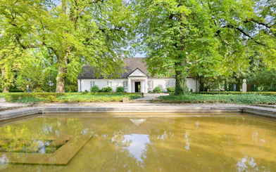 Birthplace of Frederick Chopin in Żelazowa Wola, surrounded by lush greenery and a reflecting pond.