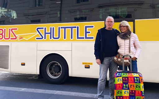 Couple with luggage in front of a shuttle bus for Rome hop-on hop-off tour from Civitavecchia.