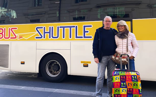 Couple with luggage in front of a shuttle bus for Rome hop-on hop-off tour from Civitavecchia.