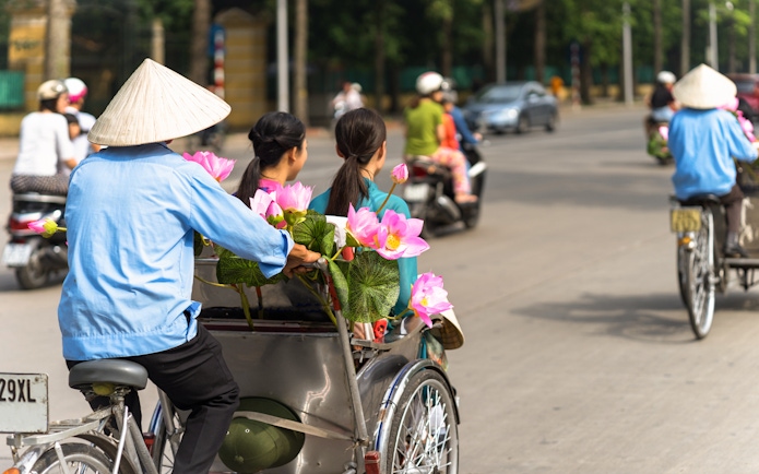 Cyclo ride with lotus flowers in Ho Chi Minh City street.