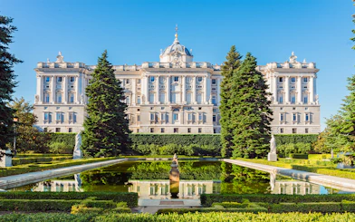 Royal Palace of Madrid exterior with garden and reflecting pool.