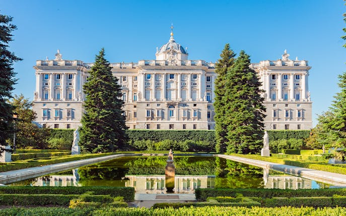 Royal Palace of Madrid exterior with garden and reflecting pool.
