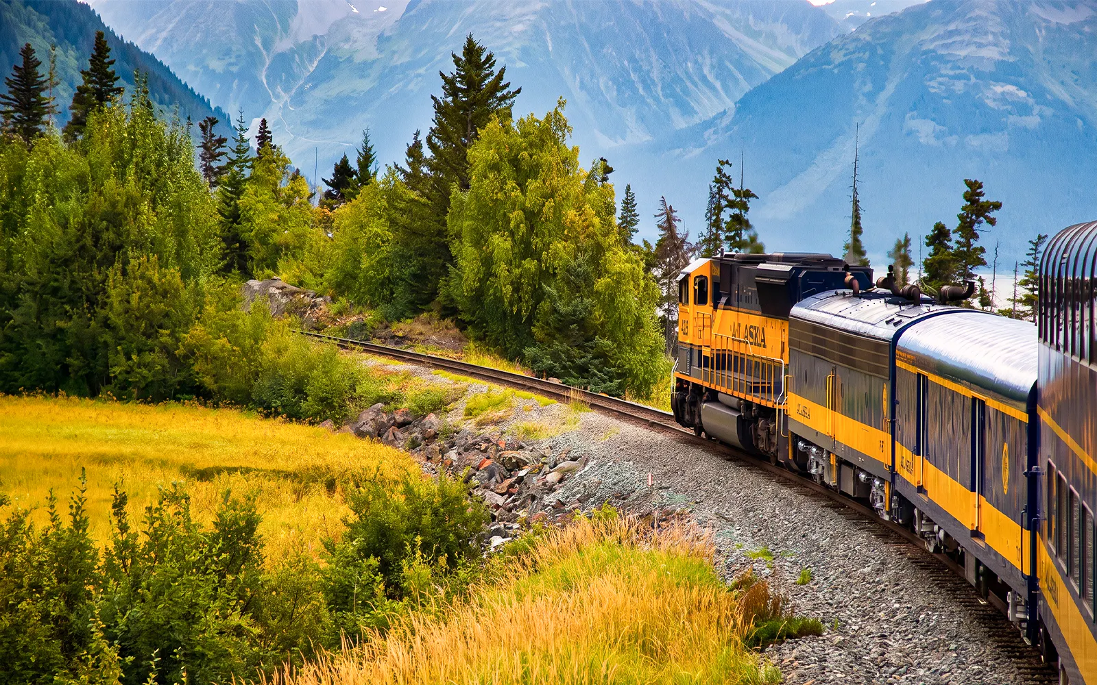 Alaska Railroad train traveling through scenic mountain landscape.
