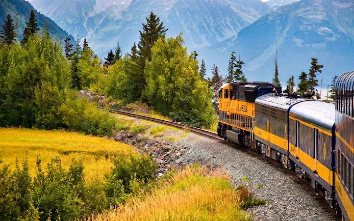 Alaska Railroad train traveling through scenic mountain landscape.
