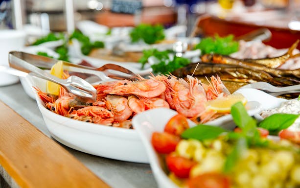 Shrimp buffet with lemon wedges and fresh herbs on a serving platter.