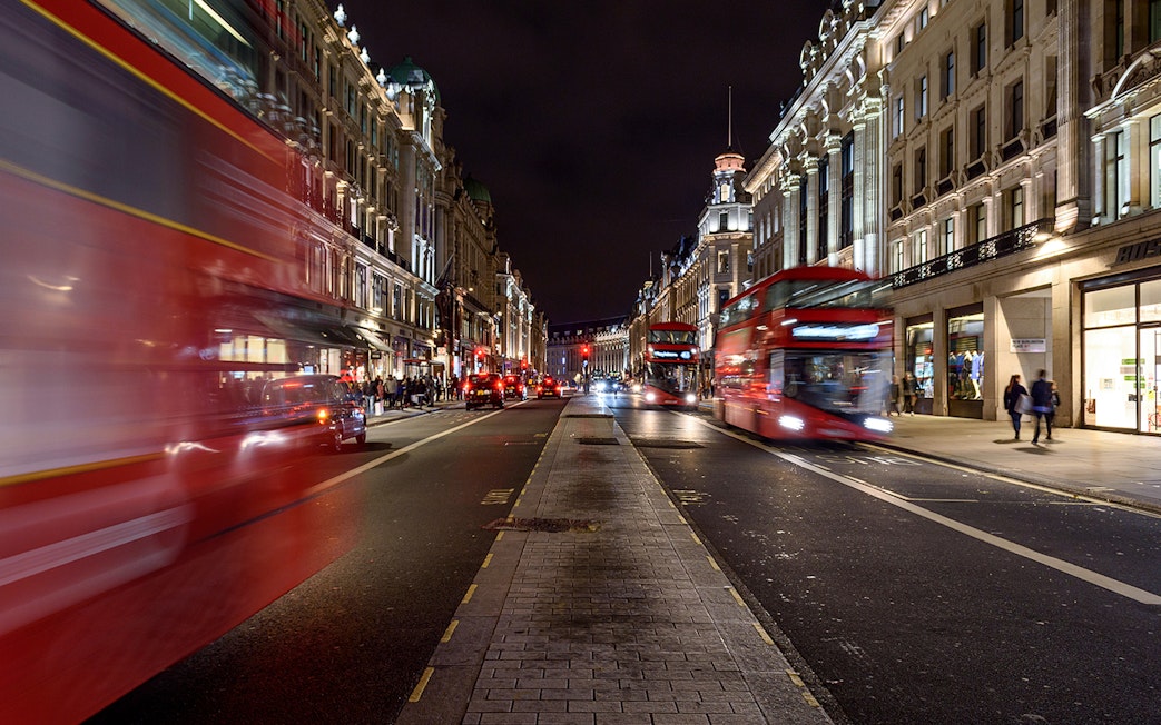 Red double-decker buses on a busy London street at night during the Big Bus Panoramic Evening Tour.
