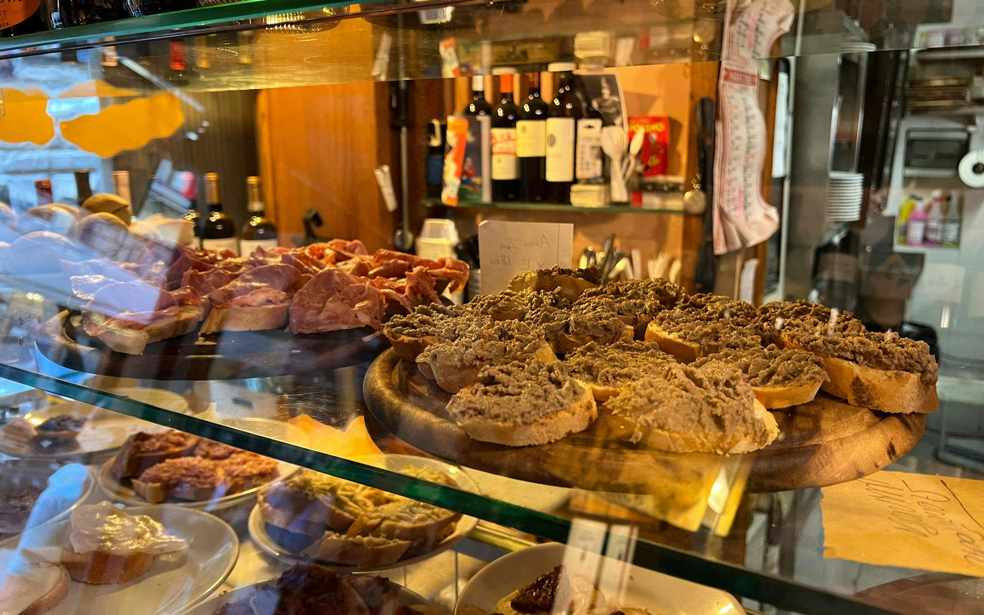 Traditional Tuscan crostini with liver pâté and cured meats in a Florence deli.
