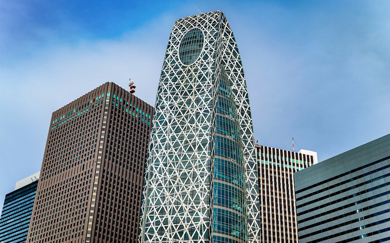 Mode Gakuen Cocoon Tower in Tokyo with its unique lattice design against a clear sky.