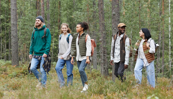 Hikers trekking through lush forest towards Piscina Irgas waterfall in Villacidro, Cagliari.
