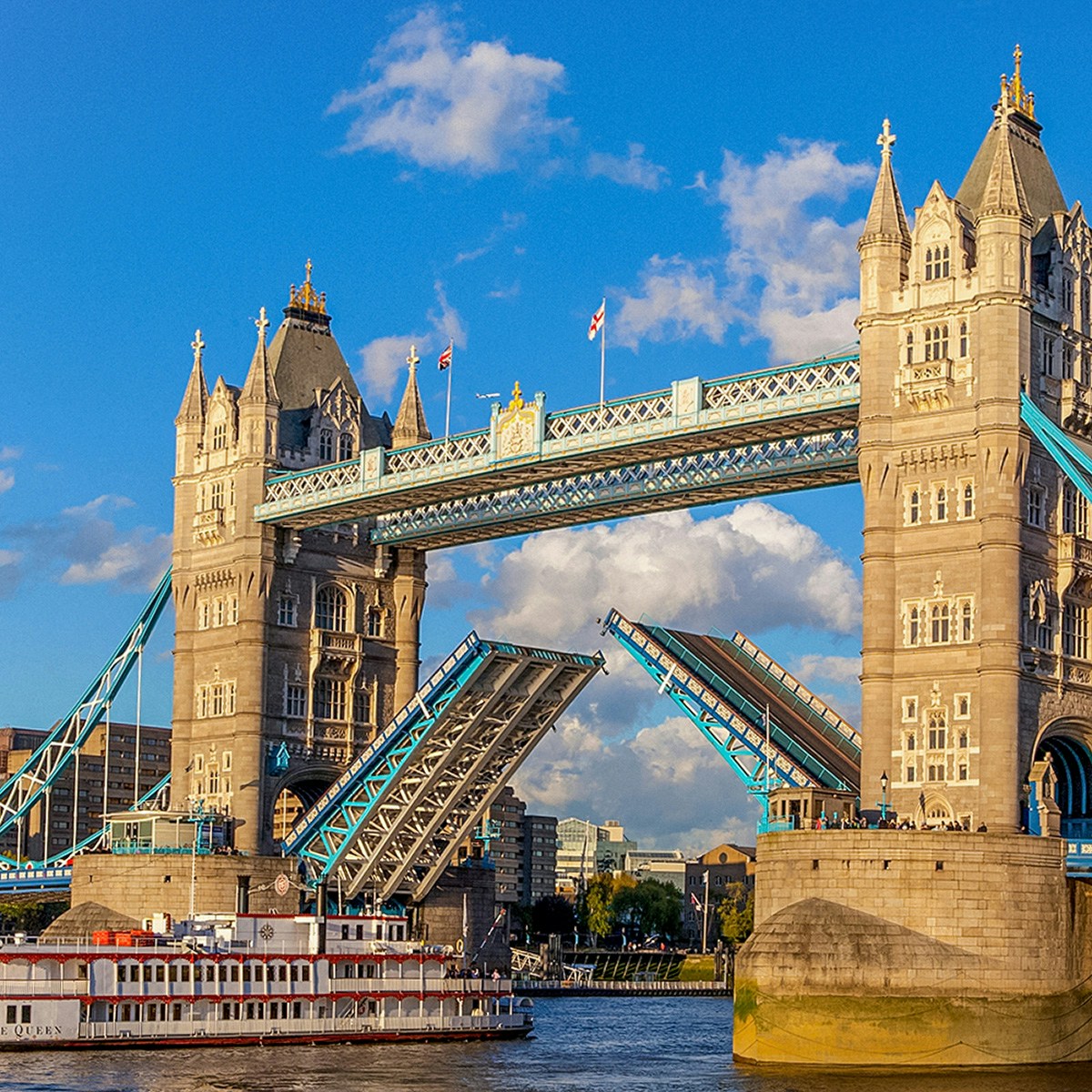 Tower Bridge in London with raised bascules and a boat passing underneath.