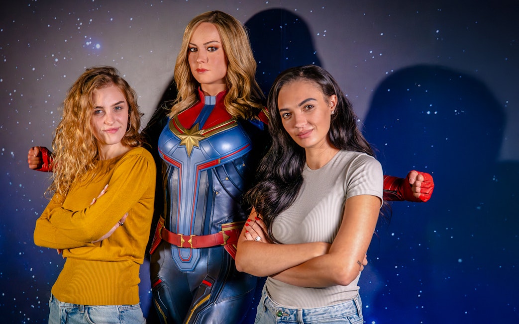 Guests posing with Captain Marvel figure at Madame Tussauds London Hall of Heroes.