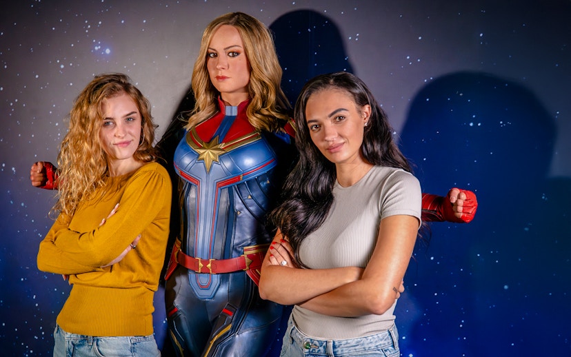 Guests posing with Captain Marvel figure at Madame Tussauds London Hall of Heroes.