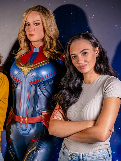 Guests posing with Captain Marvel figure at Madame Tussauds London Hall of Heroes.