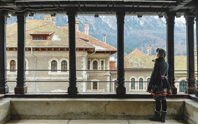Guest viewing Peles Castle courtyard through window, Sinaia, Romania.
