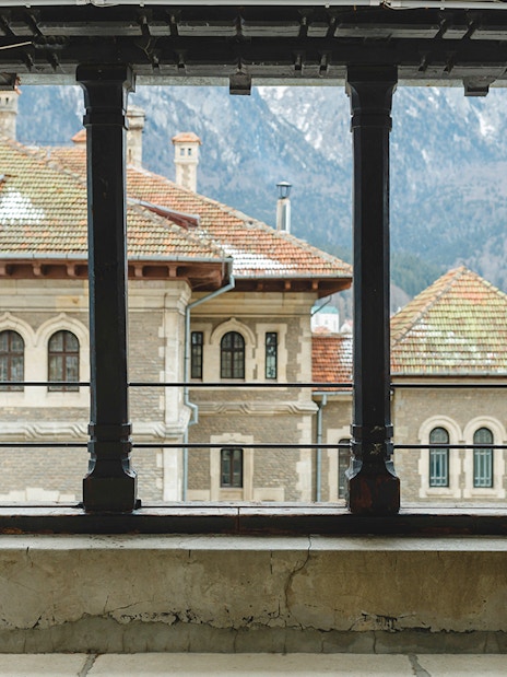 Guest viewing Peles Castle courtyard through window, Sinaia, Romania.