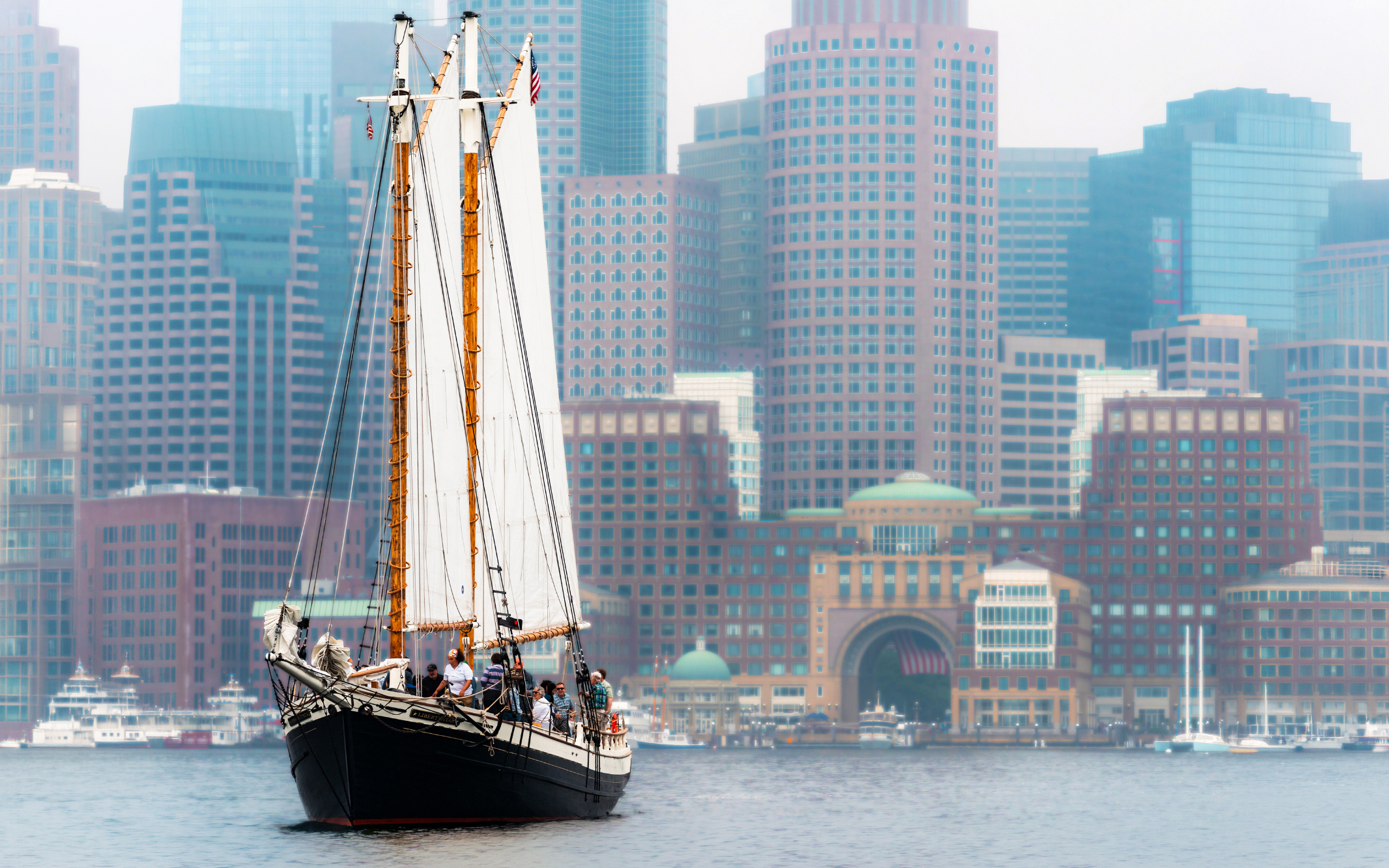 Schooner Liberty Star sailing in Boston Harbor with city skyline in background.