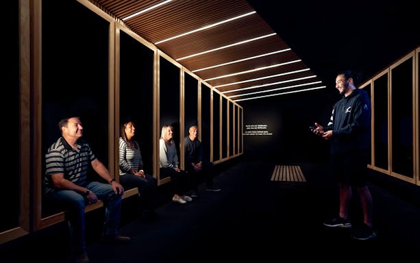Visitors seated in a dark room listening to a guide at the All Blacks Experience in New Zealand.