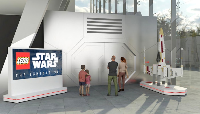 Family viewing LEGO Star Wars exhibition entrance with spaceship model.