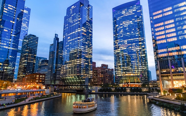 Chicago River cruise at dusk with illuminated skyscrapers in Chicago, Illinois, USA.