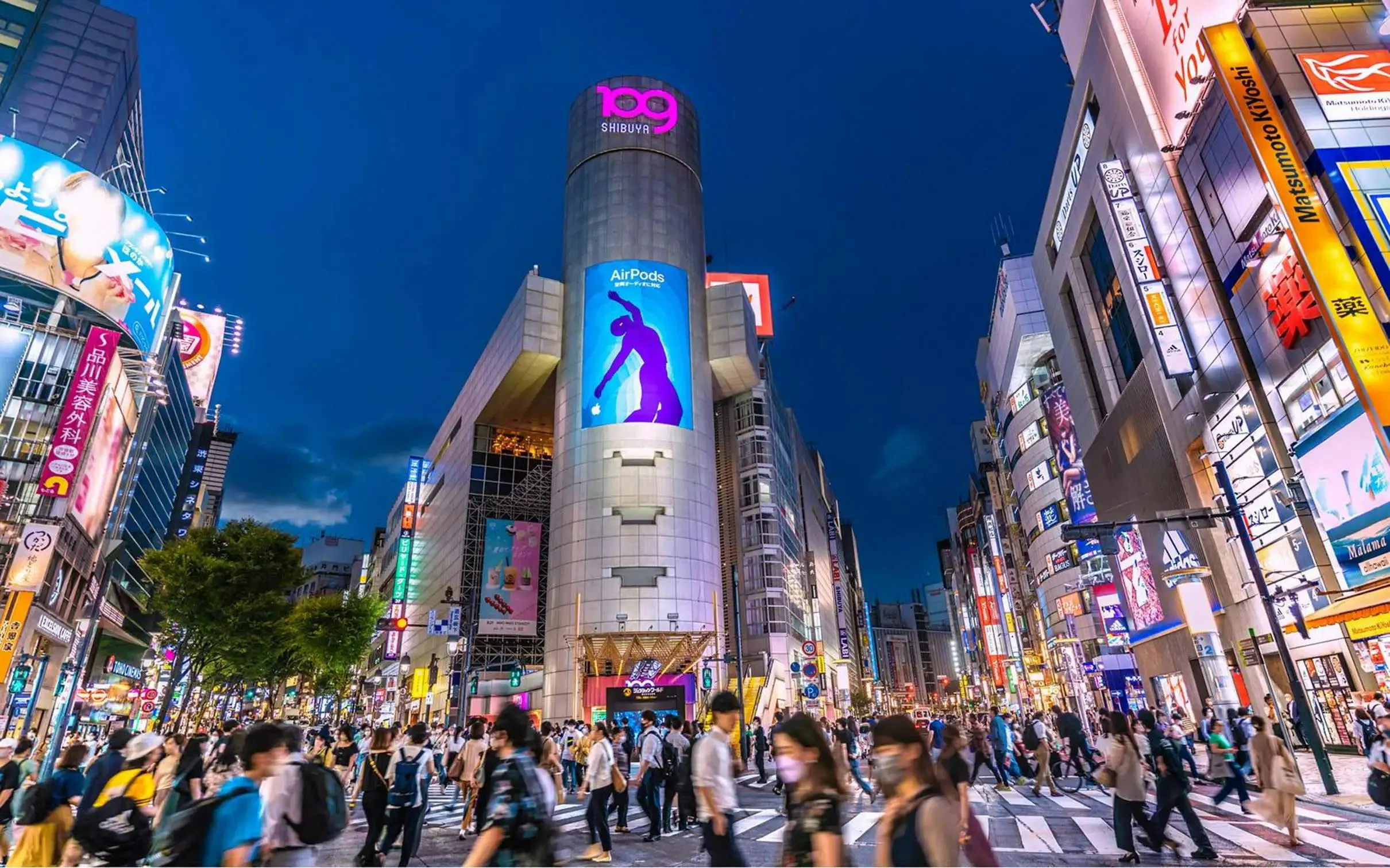 Shibuya Crossing at night, bustling with people and neon lights, Tokyo Drift 5.0 tour.